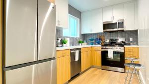La cuisine est équipée de placards blancs et d'un réfrigérateur en acier inoxydable. dans l'établissement Kingsley Courtyard Apartment, à Los Angeles