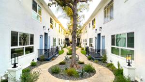une cour avec un arbre au milieu de deux bâtiments dans l'établissement Kingsley Courtyard Apartment, à Los Angeles