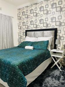 ein Schlafzimmer mit einem Bett mit einer grünen Bettdecke in der Unterkunft Q’s in Empangeni
