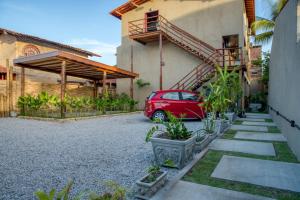 um carro vermelho estacionado em frente a uma casa em Ubud Apartments Praia do Frances na Praia do Francês