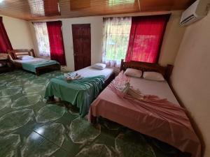 two beds in a room with red windows at Casa Tucan in Drake
