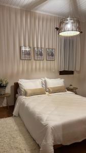 Un dormitorio con una gran cama blanca y una lámpara de araña. en House in the Woods, en Karditsa