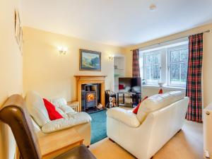a living room with two white chairs and a fireplace at Curin Cottage Strathconon in Contin