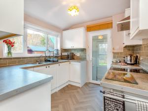 une cuisine avec des comptoirs et des placards blancs dans l'établissement Curin Cottage Strathconon, à Contin