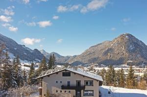 a house in the snow with mountains in the background at Dreimäderlhaus am Berg in Pfronten
