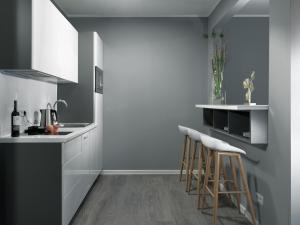a kitchen with white cabinets and bar stools at THE ROOMS - Hotel & House in Frankfurt/Main