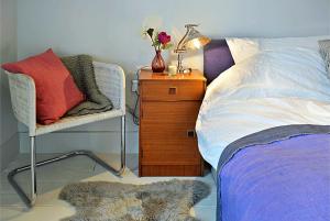 a bedroom with a bed and a chair and a night stand at Royal Parade Apartments in Harrogate