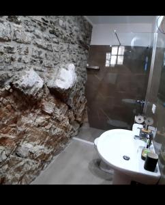 baño con lavabo y pared de piedra en Guest House J.Prifti, en Berat