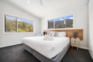a bedroom with a large bed and two windows at Stillwater Chalet B Crackenback in Crackenback