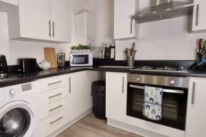 uma cozinha com armários brancos e um forno com placa de fogão em Cosy 3BR Hastings House in Maidstone Kent em Kent