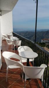 a row of white tables and chairs on a balcony at Hotel Restaurante Atalaya in Comares