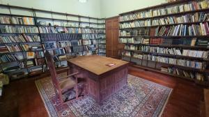 eine Bibliothek mit einem Tisch, einem Stuhl und Büchern in der Unterkunft Oceania House Hotel in Bantam Village