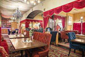 ein Restaurant mit Tischen, Stühlen und roten Vorhängen in der Unterkunft Best Western Hotel Gamla Teatern in Östersund