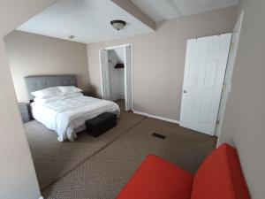1 dormitorio con cama blanca y sofá rojo en Cozy Updated 3-BR apartment near Peace Bridge, en Buffalo