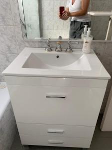 a person taking a picture of a white bathroom sink at Barrancas de Belgrano in Buenos Aires