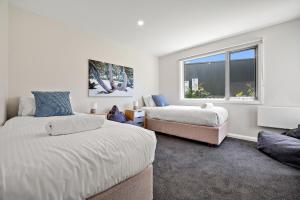 a bedroom with two beds and a window at Stillwater Chalet A - Amazing Lakefront 2BR Chalet l BBQ l Gym l Tennis l Indoor Pool in Crackenback