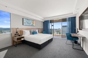 ゴールドコーストにあるクラウンプラザ サーファーズ パラダイスのベッドとデスクが備わるホテルルームです。