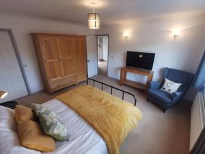 1 dormitorio con 1 cama, 1 silla y TV en Twyngaer, a spacious 3 bedroom bungalow sleeps 6, en Knighton