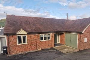 a red brick house with a green garage at Twyngaer, a spacious 3 bedroom bungalow sleeps 6 in Knighton