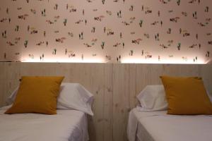 two beds with yellow pillows in a room with a wall at 201 I Posada del Mar I Encantador hostel en la playa de Gandia in Los Mártires
