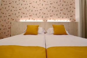 um quarto com 2 camas e almofadas amarelas em 201 I Posada del Mar I Encantador hostel en la playa de Gandia em Los Mártires