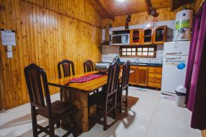 a kitchen with a wooden table with chairs and a refrigerator at Cabañas Riberas del Paraná in Puerto Iguazú