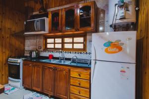 a kitchen with a white refrigerator and wooden cabinets at Cabañas Riberas del Paraná in Puerto Iguazú