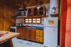 a kitchen with wooden cabinets and a white refrigerator at Cabañas Riberas del Paraná in Puerto Iguazú