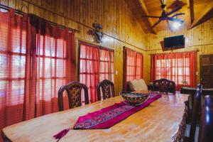 a dining room with a wooden table and red curtains at Cabañas Riberas del Paraná in Puerto Iguazú