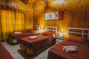 sypialnia z 3 łóżkami i drewnianymi ścianami w obiekcie Cabañas Riberas del Paraná w mieście Puerto Iguazú