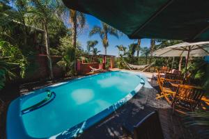 a swimming pool with a hammock and an umbrella at Cabañas Riberas del Paraná in Puerto Iguazú