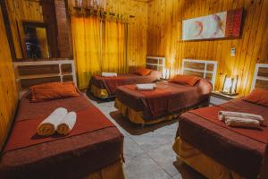 a room with three beds in a wooden room at Cabañas Riberas del Paraná in Puerto Iguazú