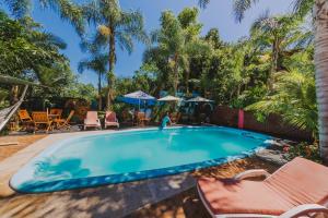 a pool with chairs and umbrellas in a yard at Cabañas Riberas del Paraná in Puerto Iguazú