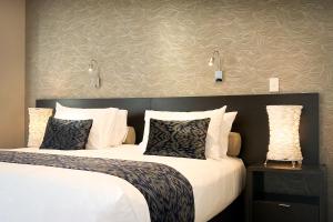 duas camas num quarto de hotel com almofadas brancas em The Sails Nelson em Nelson