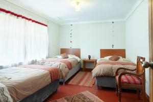 a bedroom with two beds and a chair and a window at Magic Cusco in Cusco