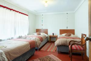 1 dormitorio con 2 camas, silla y ventana en Magic Cusco, en Cusco