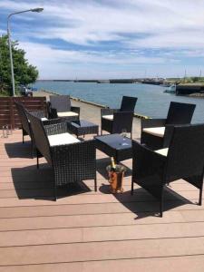 een groep stoelen en tafels op een terras bij het water bij Pier39 Uchiumi Cozy house located in front of the sea and harbor! in Miyazaki