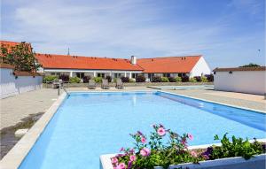 a large blue swimming pool with flowers in a yard at Stunning Apartment In Gudhjem With Kitchen in Gudhjem