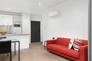 Il comprend un salon avec un canapé rouge et une cuisine. dans l'établissement 108 Astral Apartments, à Melbourne