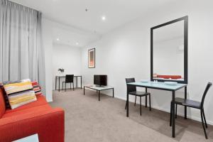 - un salon avec un canapé rouge, une table et des chaises dans l'établissement 108 Astral Apartments, à Melbourne