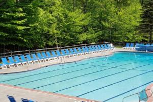 a large swimming pool with blue chairs next to it at Cozy Poconos Ranch Home with Pool Access, Near Lake! in Gouldsboro