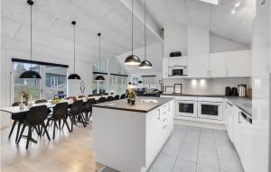 a large white kitchen with a table and chairs at Stunning Home In Væggerløse With Sauna in Marielyst