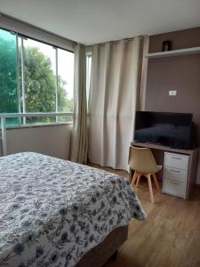 1 dormitorio con cama, escritorio y ventana en Casa da Silvana -Piso superior, en Bombinhas