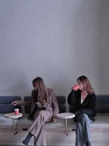 FAV TOKYO Nishinippori في طوكيو: اثنتان من النساء جالسات على أريكة يشربن من كوب