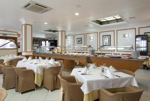 a restaurant with white tables and chairs and a counter at Hotel Olympia Ronda I in El Puig