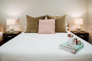 een slaapkamer met een bed met een roze kussen en 2 lampen bij The Lodge Jamberoo in Jamberoo