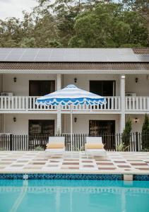 a house with a pool and two chairs and an umbrella at The Lodge Jamberoo in Jamberoo