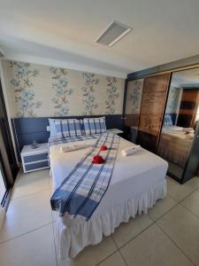 a bedroom with a large white bed with blue pillows at Apartamento a beira mar com piscina estilo resort in Cabedelo