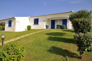 a white house with blue shutters and a yard at Residenze Mare e Pineta in Budoni