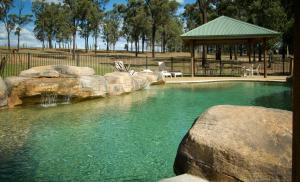 a pool of water with rocks and a gazebo at RidgeView in Pokolbin